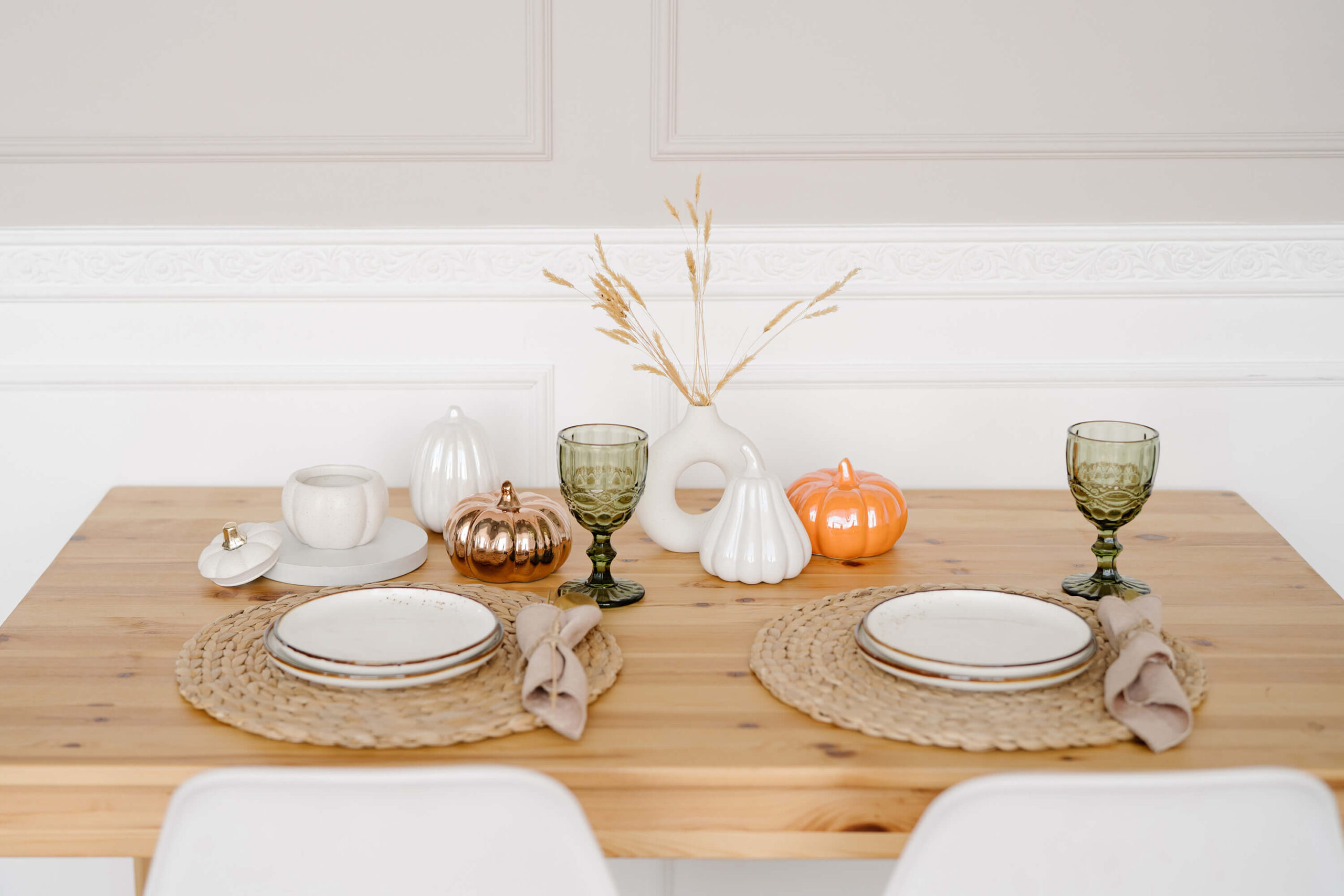 Thanksgiving table with plates, pumpkins, and goblets